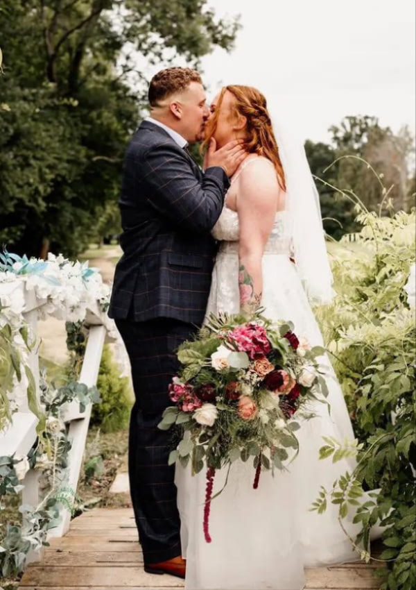 Bride and groom with wedding flowers by Flowers By Rosie